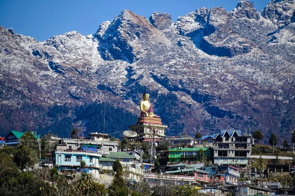 A statue of Buddha in front of the mountains in Tawang